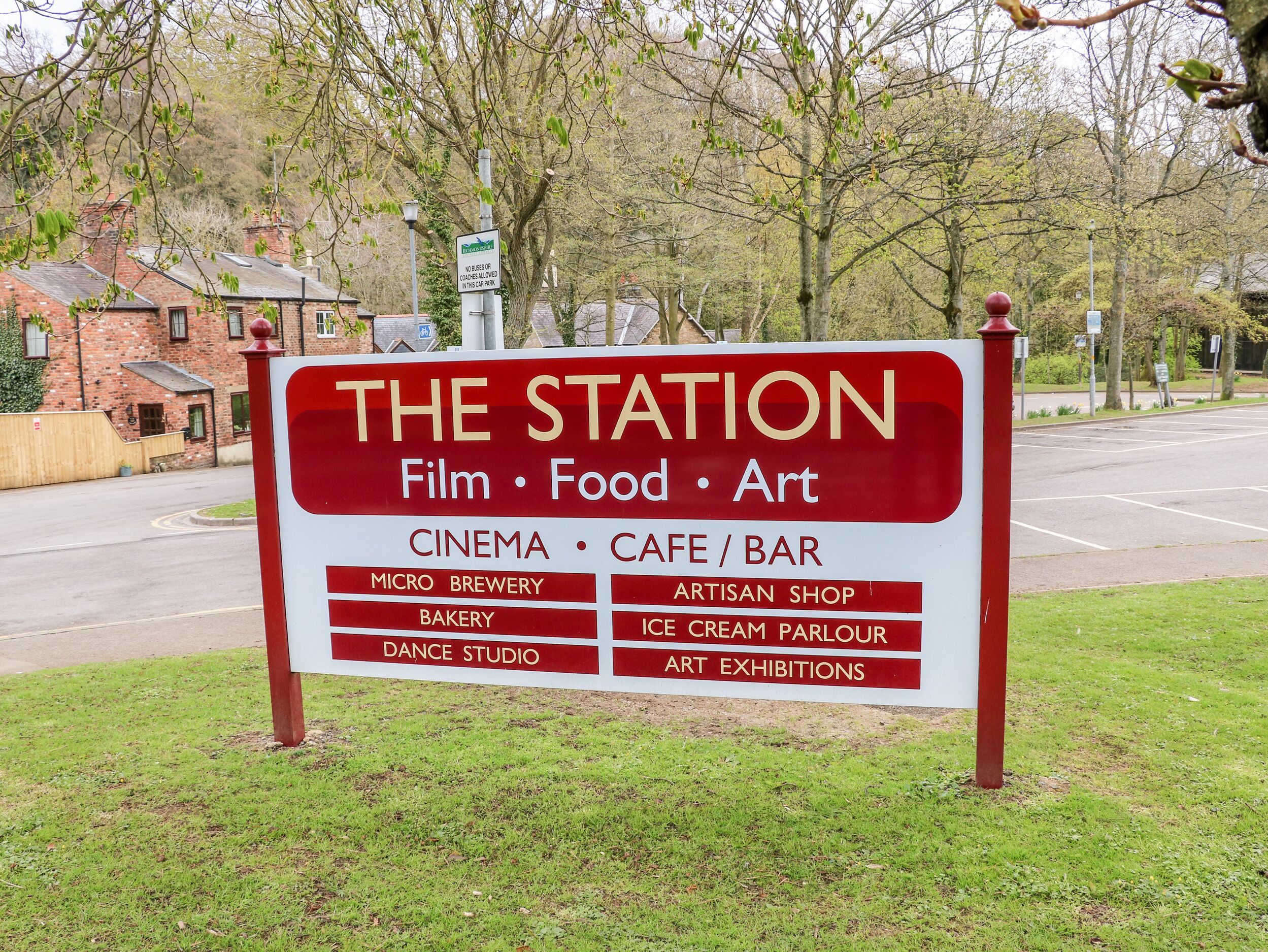 A sign for 'The Station' listing amenities like a cinema, cafe/bar, micro brewery, bakery, dance studio, artisan shop, ice cream parlour, and art exhibitions.