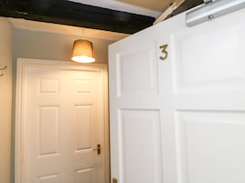 A white door with a brass number "3" and a hanging light fixture above it.