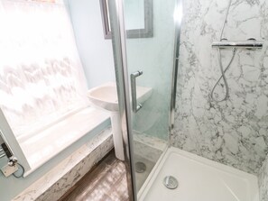 A bathroom with a glass shower enclosure, a white sink, and a marble-tiled shower area. - 3 Kings Mews (Richmond)