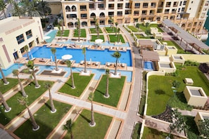 A hotel with a large central pool, multiple balconies, and a well-maintained garden area.