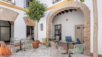 Un patio al aire libre con una mesa redonda, sillas y plantas en macetas.