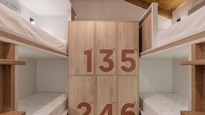 Une chambre avec des lits superposés en bois et une armoire centrale portant les numéros 135 et 246.