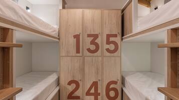 Une chambre avec des lits superposés en bois et une armoire centrale portant les numéros 135 et 246.