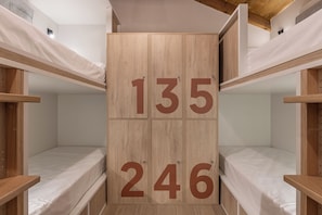 Une chambre avec des lits superposés en bois et une armoire centrale portant les numéros 135 et 246.