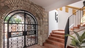 Un arc en pierre menant à un escalier surmonté d’une grille en fer forgé.