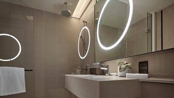 A modern bathroom with a glass shower enclosure, a vanity with a mirror, and a towel rack.