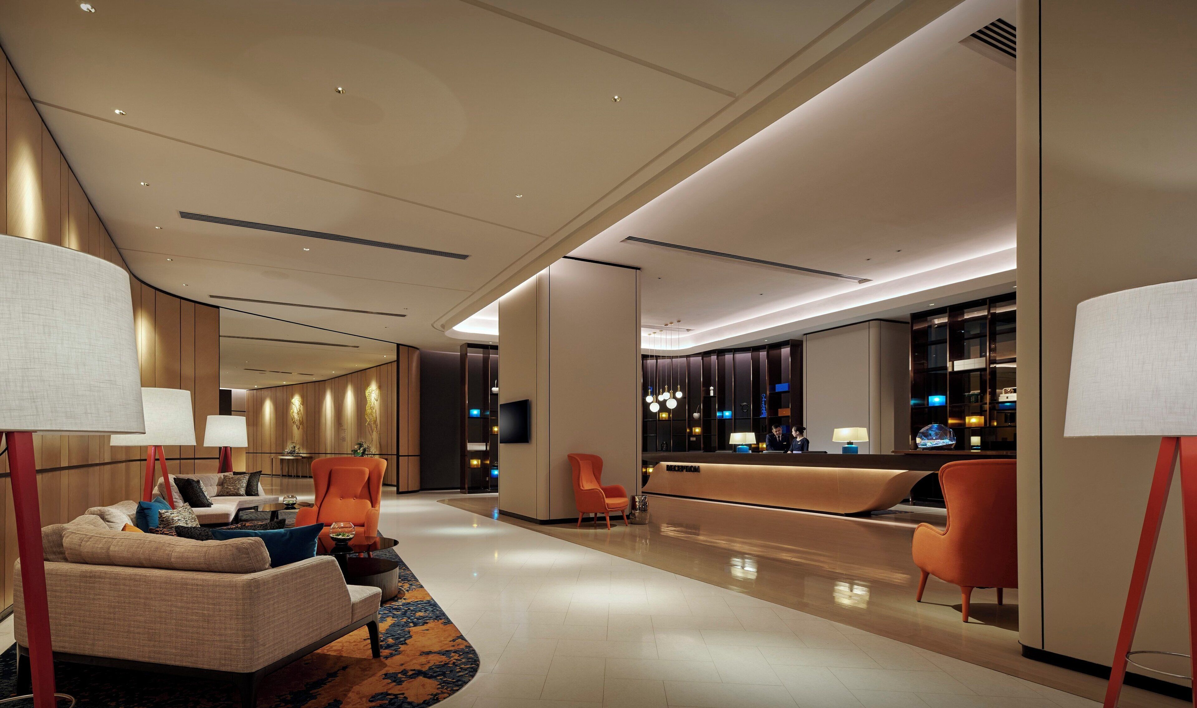 Eine moderne Hotelhalle mit einer Rezeption, Sitzbereichen und einem großen Fenster.