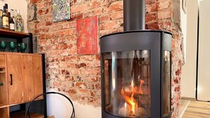 Un soggiorno moderno con una stufa a legna, un muro in mattoni e un mobile in legno.