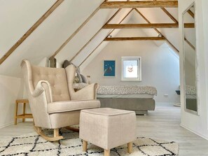 A loft-style room with a high ceiling, a beige sofa, a matching ottoman, and a patterned rug. - StylishHomes NEST - A Cosy Adventure (Frauental an der Lassnitz)