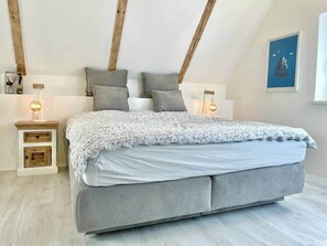 Una camera da letto con un letto, comodini e un punto luce a parete.