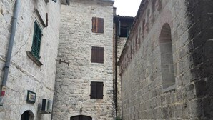A narrow alleyway with stone buildings, a small table, and benches. - Athos Guesthouse (Kotor)