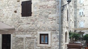 A stone building with a small window, a bench, and a lamp post. - Athos Guesthouse (Kotor)