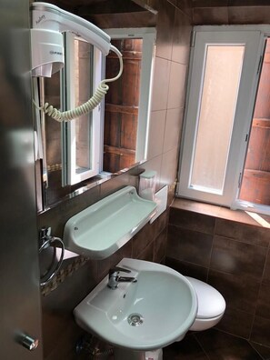 A bathroom with a toilet, a sink, and a mirror. - Athos Guesthouse (Kotor)