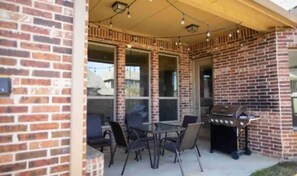 Enjoy al fresco dining on the patio, where a grill and table with chairs await, surrounded by string lights.