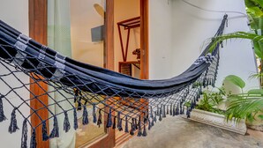 A hammock tied between a wooden post and a glass door, with a potted plant beside it. -  Pousada Vila Galea (Itacaré)