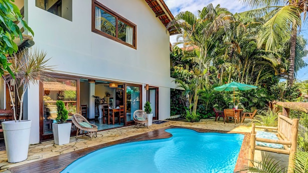A modern house with a swimming pool, wooden deck, and tropical plants. -  Pousada Vila Galea (Itacaré)