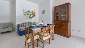 Un comedor con una mesa de madera, sillas, un armario y un sofá.