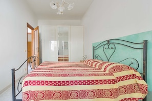 Quarto com uma cama, um guarda-roupa e um espelho.