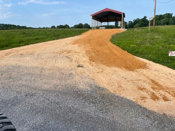 Un camino de grava que lleva a una construcción de techo rojo en un entorno rural.