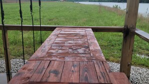 A wooden bench with a metal railing, overlooking a grassy area and a body of water. - Reconnect with nature at this unforgettable escape (RV NOT INCL'D). (Clifton)