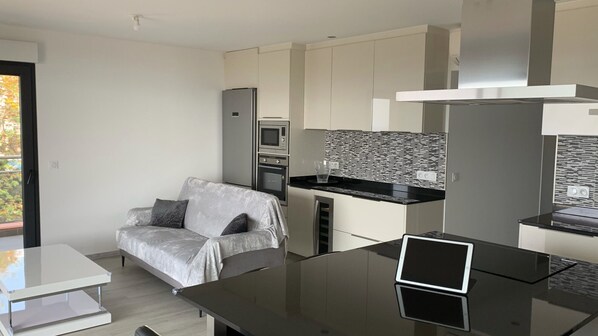 A modern kitchen with a built-in microwave, oven, and a black countertop.
