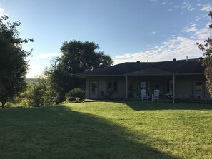 A single-story house with a covered porch, a lawn, and trees in the background. - Upper Iowa River Valley Overlook, Peaceful Country Escape (Decorah)