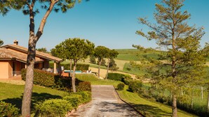 Une propriété située en zone rurale, comprenant une maison, une allée en gravier et de la végétation luxuriante tout autour.