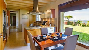 Une cuisine moderne avec un coin repas, une vue sur l’extérieur et une grande fenêtre.