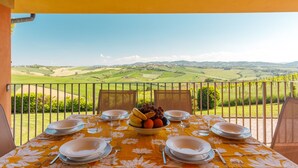 Une table dressée pour quatre personnes, avec un saladier de fruits et des verres, donnant sur un paysage magnifique.