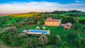 A large villa with a swimming pool, surrounded by lush greenery and hills. - Podere Pratovecchio 14+2, Emma Villas (Montefollonico)