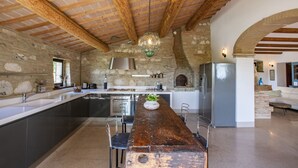 Una cocina moderna con una isla central, paredes de piedra y vigas de madera a la vista.