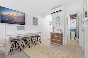 A modern kitchen with a TV, bar stools, and a decorative wall piece.