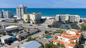 A coastal hotel area with multiple buildings, a parking lot, and a pool.