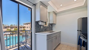 Une cuisine moderne dotée d’une grande fenêtre, d’un balcon avec vue sur la piscine et d’un réfrigérateur.