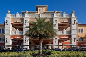 Fachada imponente de un hotel con el logotipo 'WR' bien visible, varios balcones y una palmera en el centro.