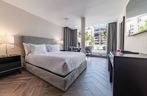 Een moderne hotelkamer met een groot bed, een bureau en uitzicht op de stad.