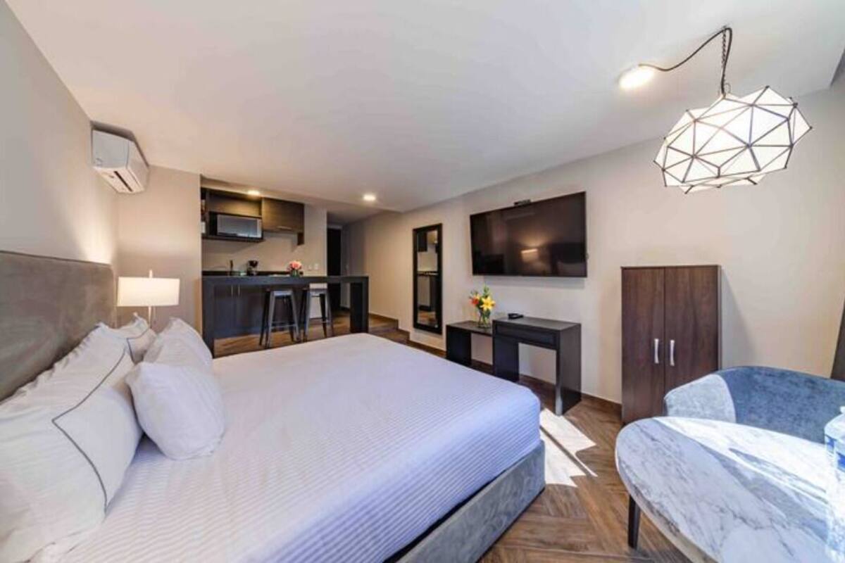 Ein modernes Hotelzimmer mit einem großen Bett, einem Schreibtisch, einem Fernseher und einer Küchenzeile.