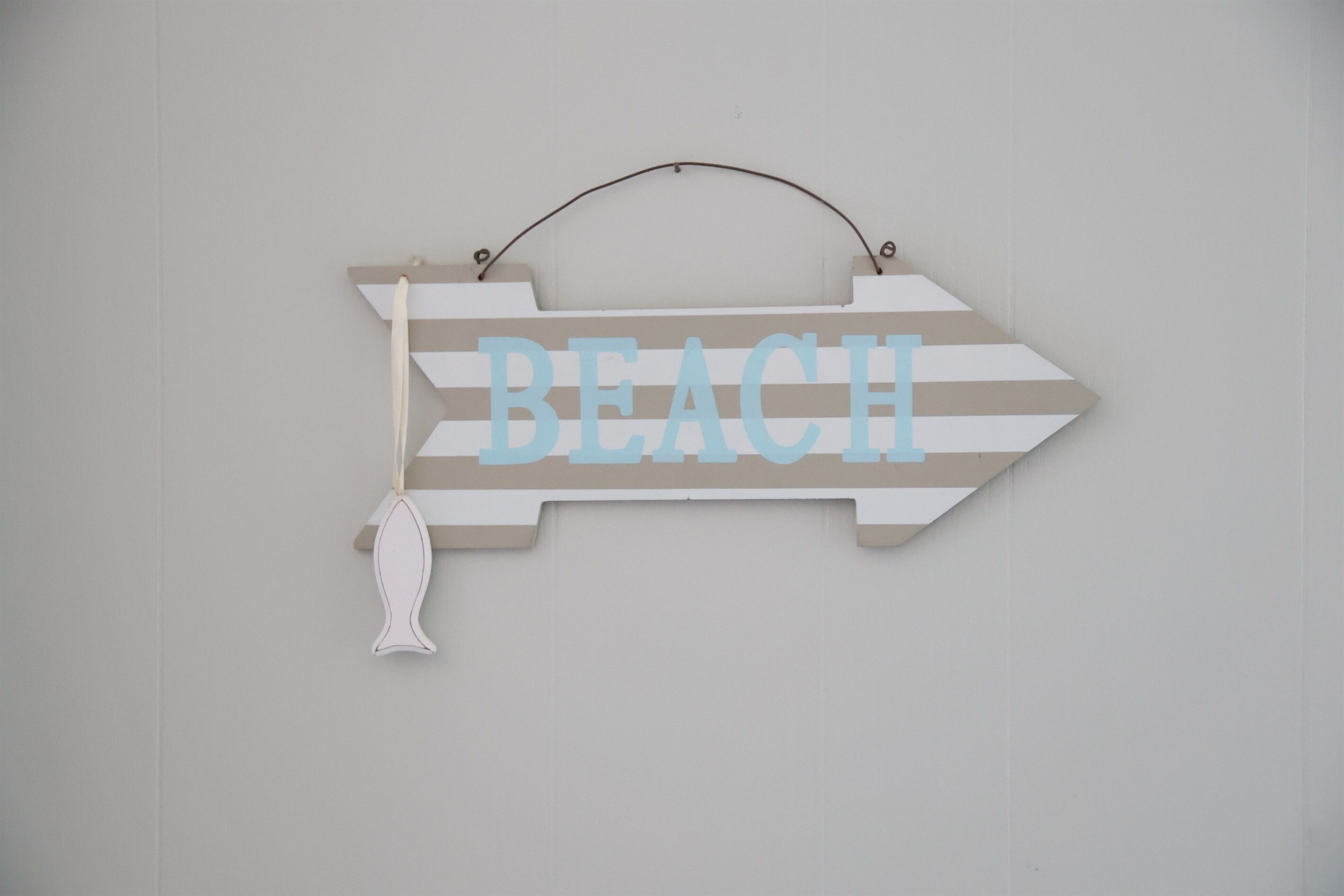 Un letrero direccional con la palabra 'BEACH' en letras grandes, fijado a una pared.