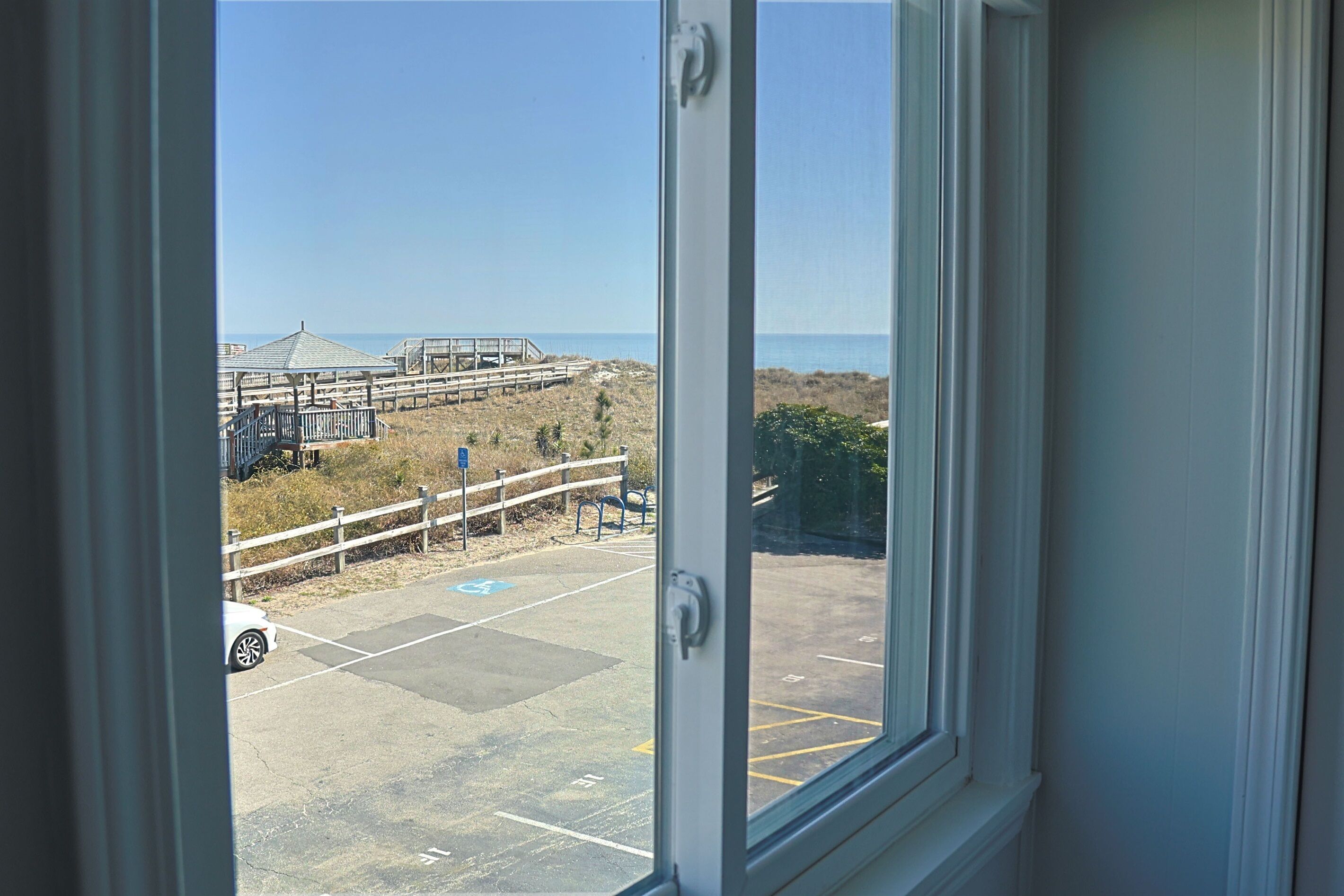 A view of a parking area with a beach and a wooden structure in the background.