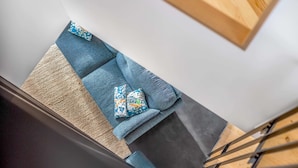 A staircase with a blue cushioned bench and patterned cushions.