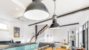 A modern kitchen with a central island, a dining area with a wooden table, and a staircase leading to another level.