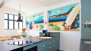 A modern kitchen with a large island, a coffee maker, and a clock on the wall.