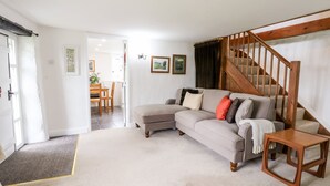 Una sala de estar con un sofá seccional color beige, una mesa de centro de madera y una escalera con barandilla de madera.
