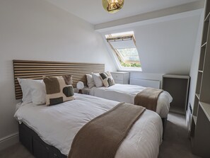 Quarto com duas camas, um claraboia e um guarda-roupa.