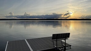 A calm body of water with a dock and a bench. - Spacious, three bedroom cottage on beautiful Lake Metonga. (Crandon)