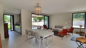 A modern living room with a dining area, large windows, and a view of the outdoors. - Charming new villa for 6 people near sperone and bonifacio (BONIFACIO)