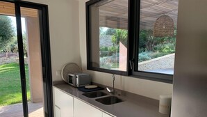 A modern kitchen with a built-in microwave, a sink, and a window overlooking a garden. - Charming new villa for 6 people near sperone and bonifacio (BONIFACIO)