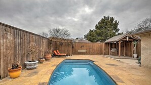A backyard with a swimming pool, wooden fence, and outdoor seating. - Collins Family-Friendly Texas Home with Private Pool! (Garland)