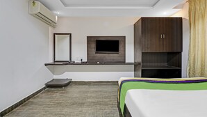 A hotel room with a bed, a desk with a flat-screen TV, a mirror, and a wardrobe. - Treebo JJ Residency (Bengaluru)