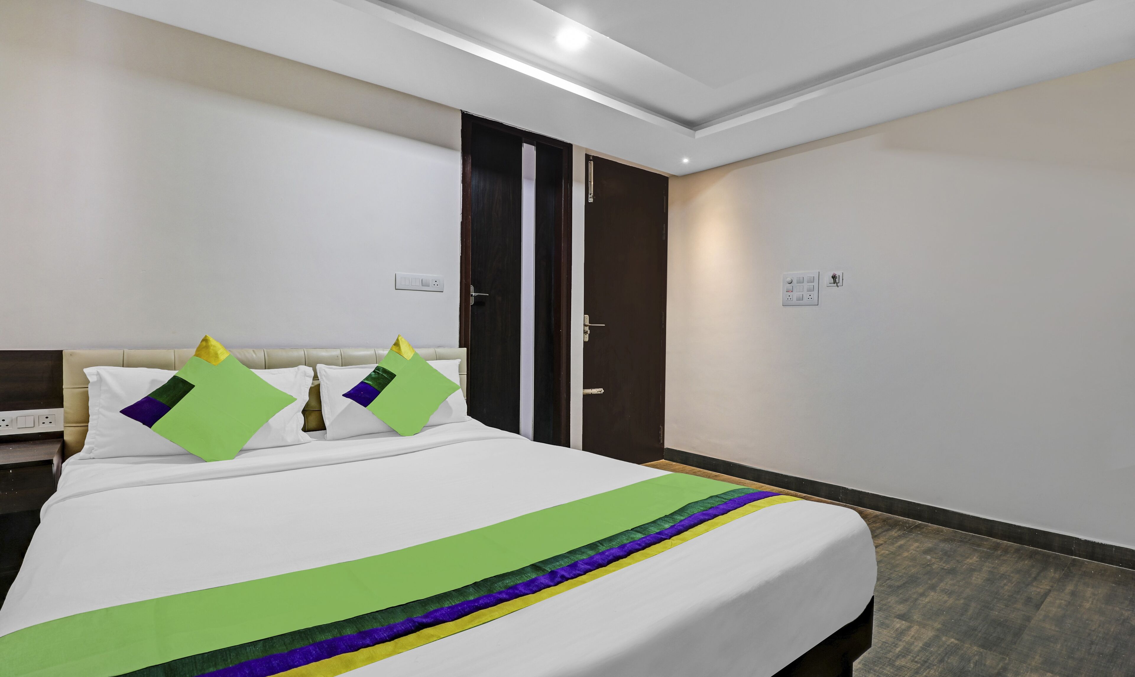 A hotel room with a bed, a nightstand, a wardrobe, and a door.